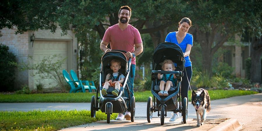 Family Walking with Two Children in Strollers with Dog